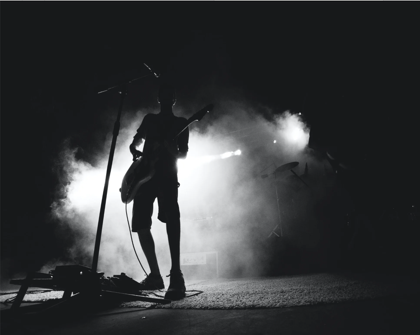 Artist silhouette on stage with smoke and spotlights